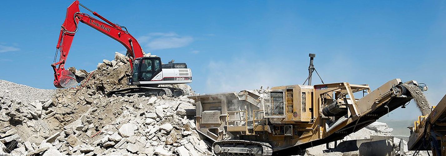 Link-Belt excavator feeding a mobile crushing and screening plant on a concrete rubble pile